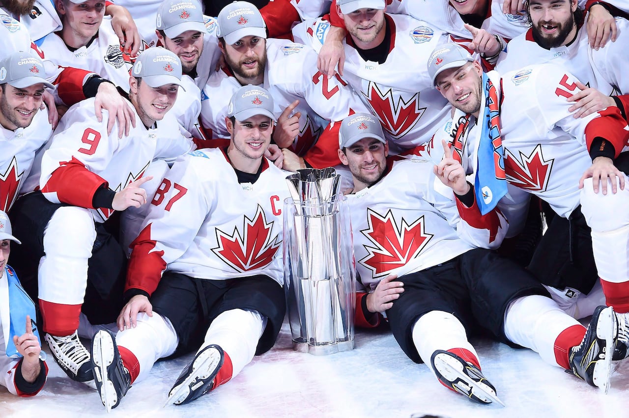 A group of hockey players sits on the ice with a trophy.