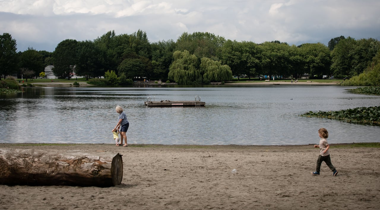 Children and a mother are seen on a lakeside beach.