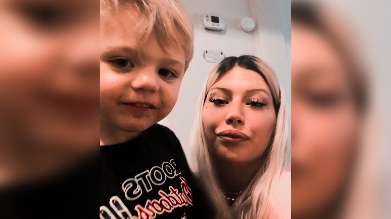 A woman smiles at the camera, there's a young boy beside her. 