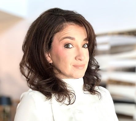 Woman wearing white looks at camera.