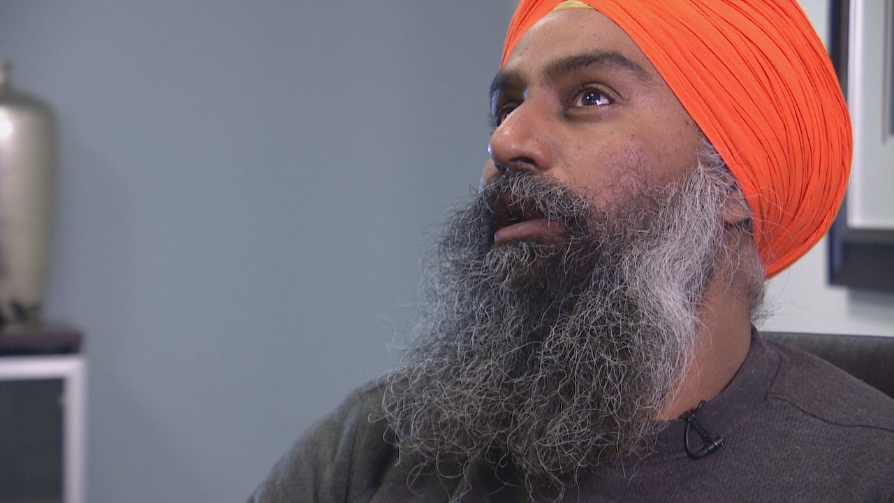 Bearded man with a turban looks off camera