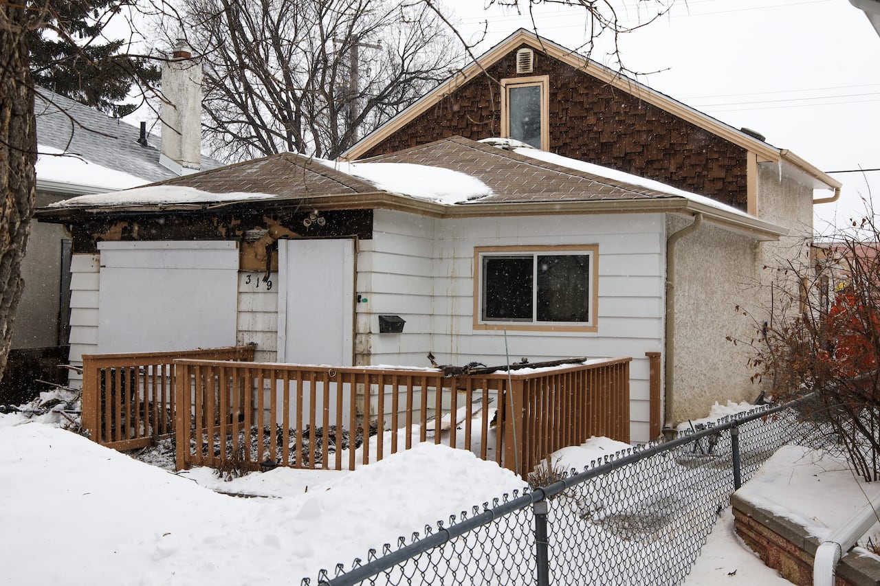 A small home is seen boarded up in winter after a fatal fire.