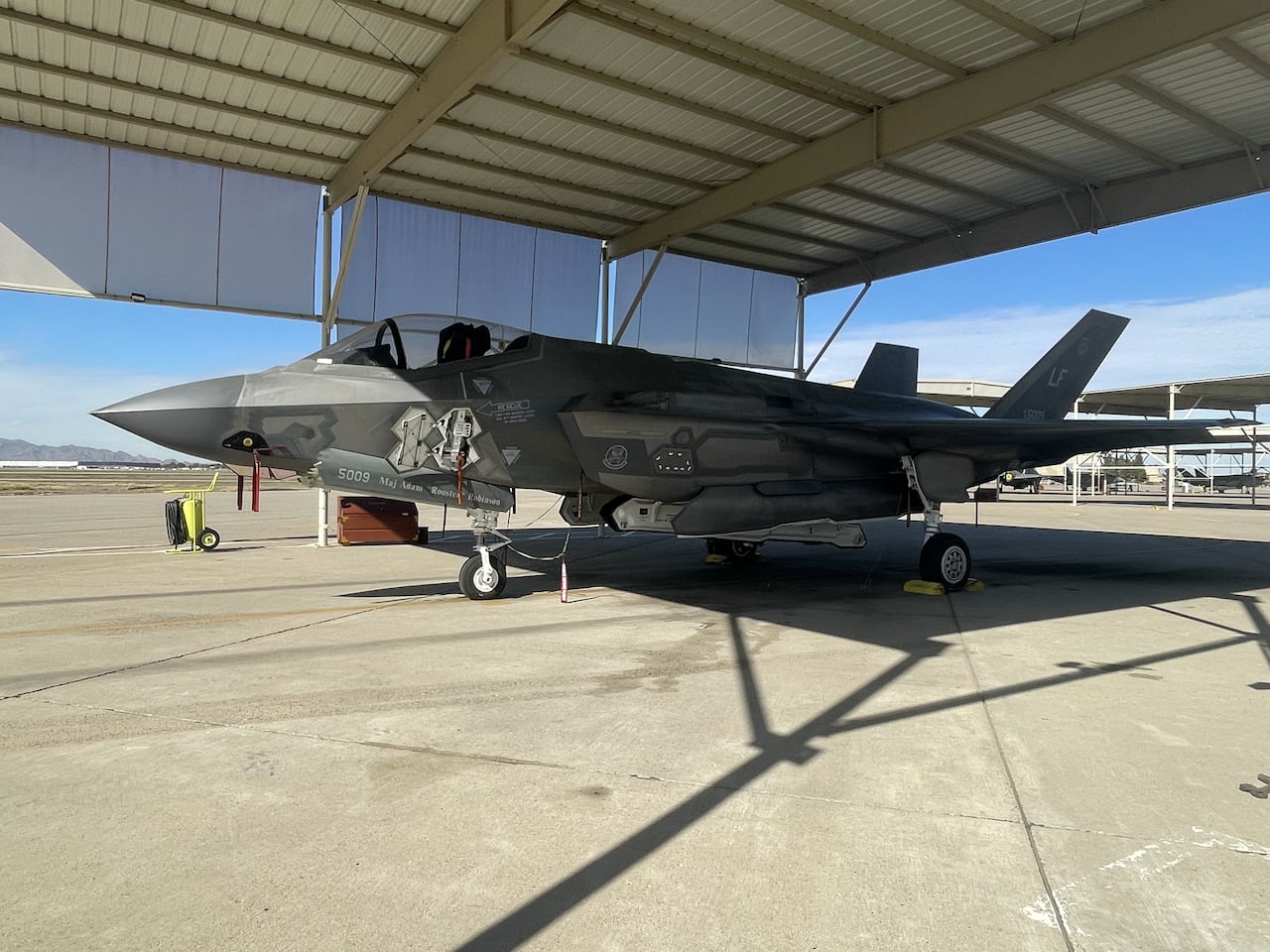 An f-35 fighter jet sits in a hangar on an air base. 