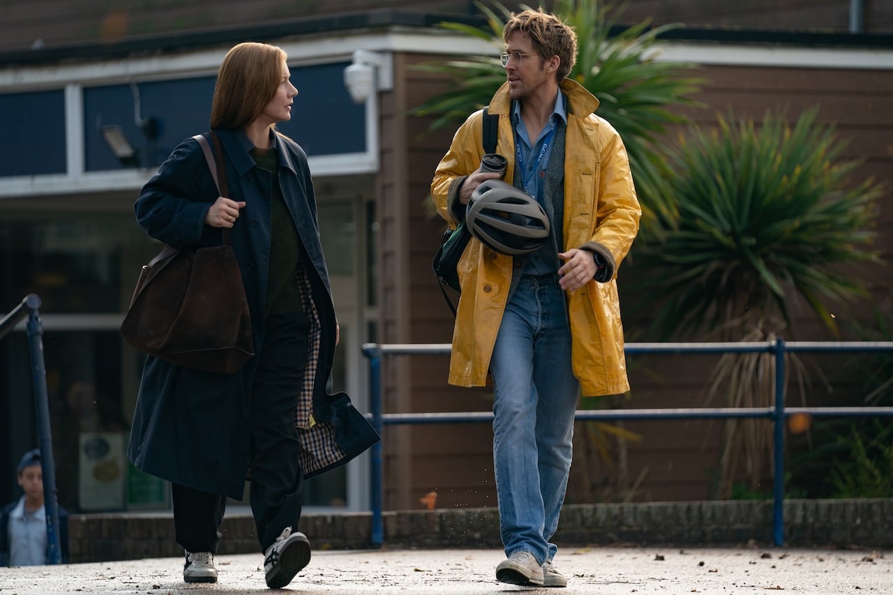 A man and woman walk while speaking to one another.