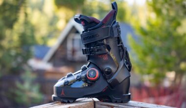 Closeup of black Atomic Nexus 130 BOA ski boot on wooden railing with blurry trees in background