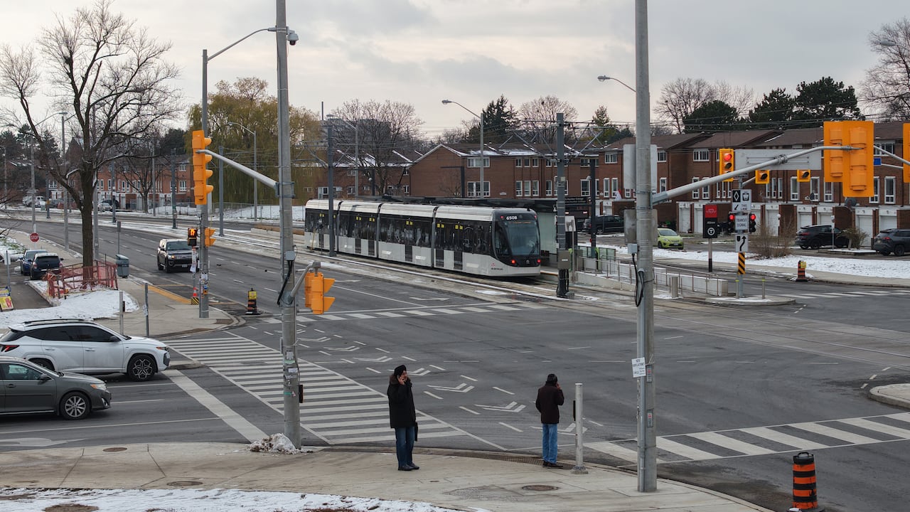 A four-car transit vehicle sits at a residential intersection