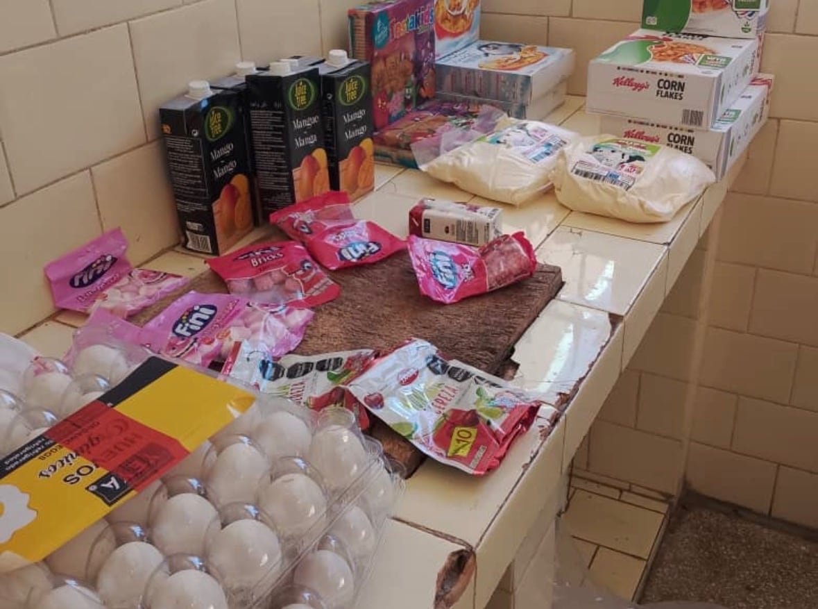 A table full of food like eggs, candy, juice, cereal and powdered milk