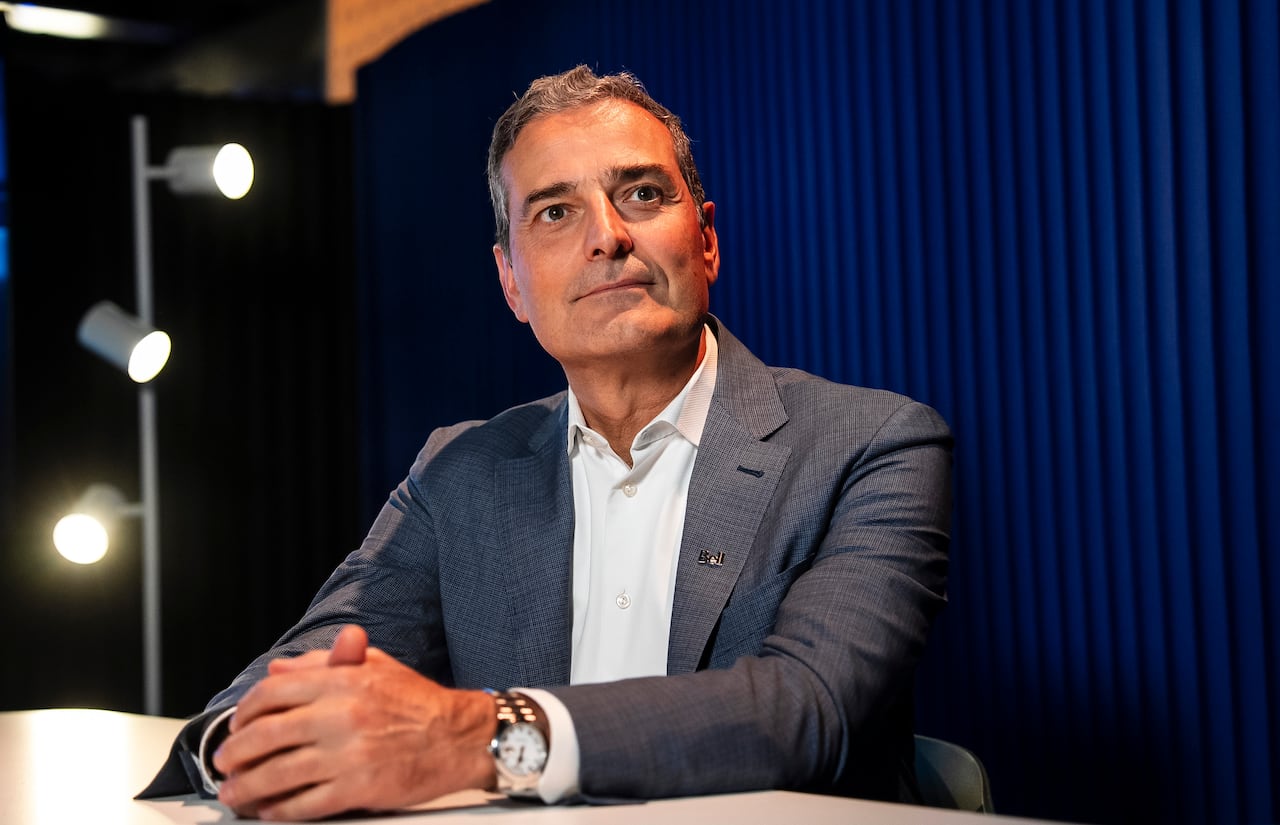 A man in a suit sits with his hands folded on a table.
