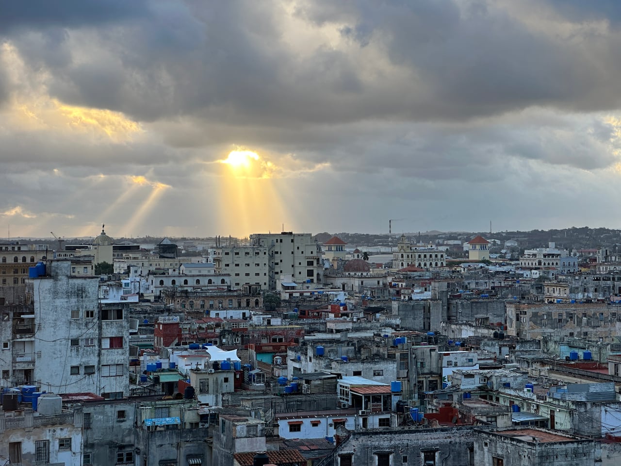 The sun breaks through clouds in a city.