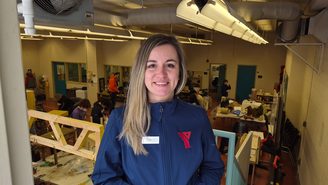 A woman wearing a jacket with the YMCA logo smiles at the camera.