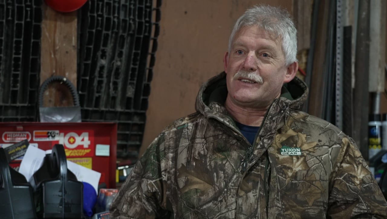 A man in a camouflage jacket stands in front of a toolbox