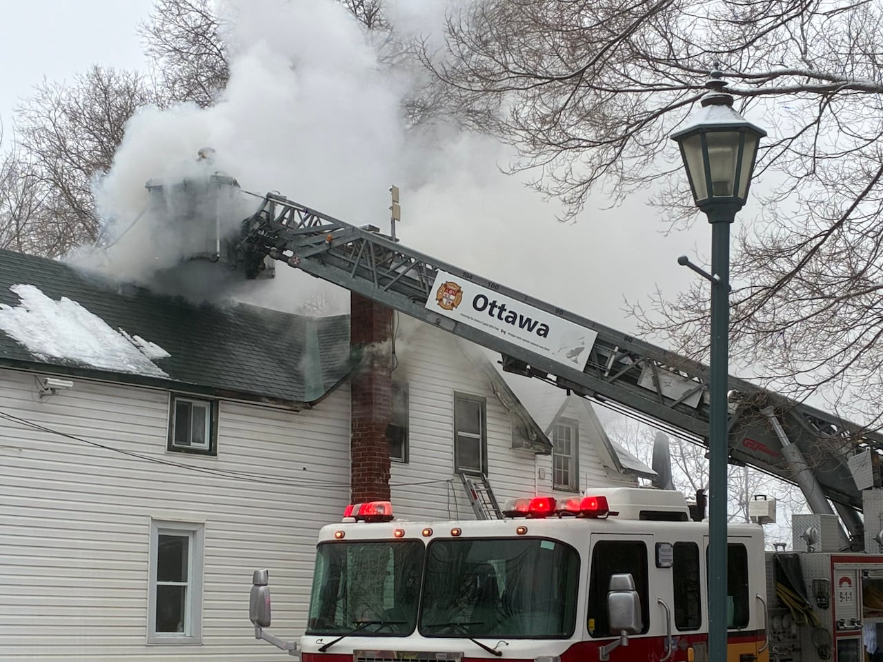 a ladder on a fire truck above smoke coming from a house.