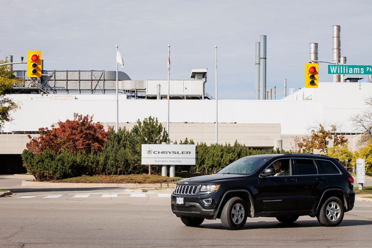An SUV near the entrance of a vehicle assembly plant with signage that reads: Chrystler Brampton assembly.