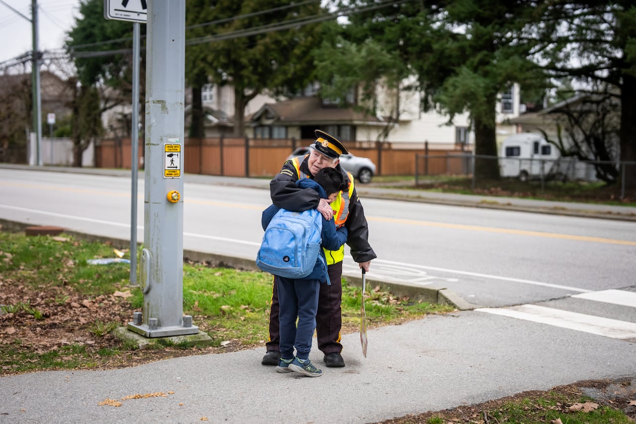 A woman hugs a small boy with a blue backpack