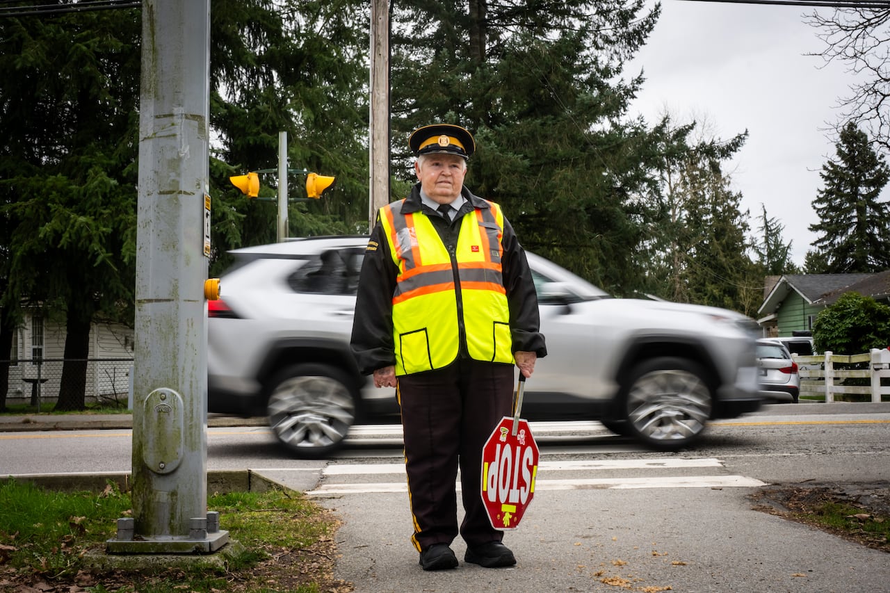 A woman wearing a neon vest and hat, holding a stop sign