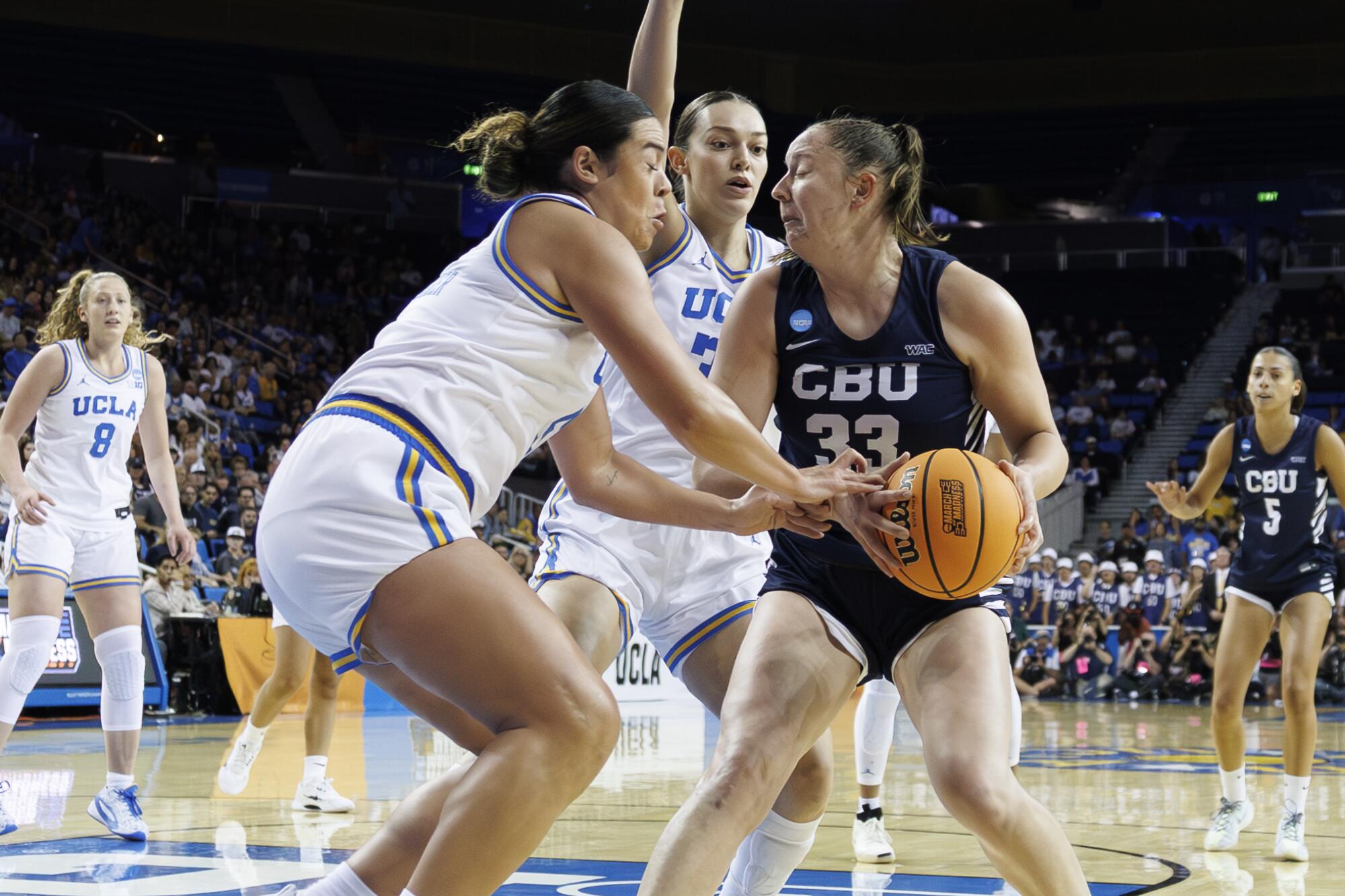 UCLA's Charlisse Leger-Walker and Angela Dugalic swarm California Baptist forward Grace Schmidt.