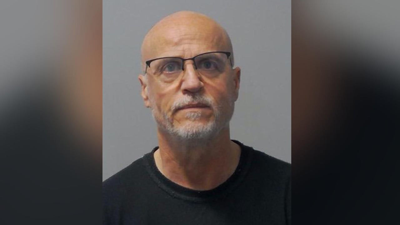 A police mug shot of a man with glasses.