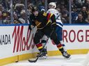 Victor Mancini of the Vancouver Canucks gets away from a hit by Nick Paul of the Tampa Bay Lightning during the second period of NHL action at Rogers Arena on March 19, 2026 in Vancouver.