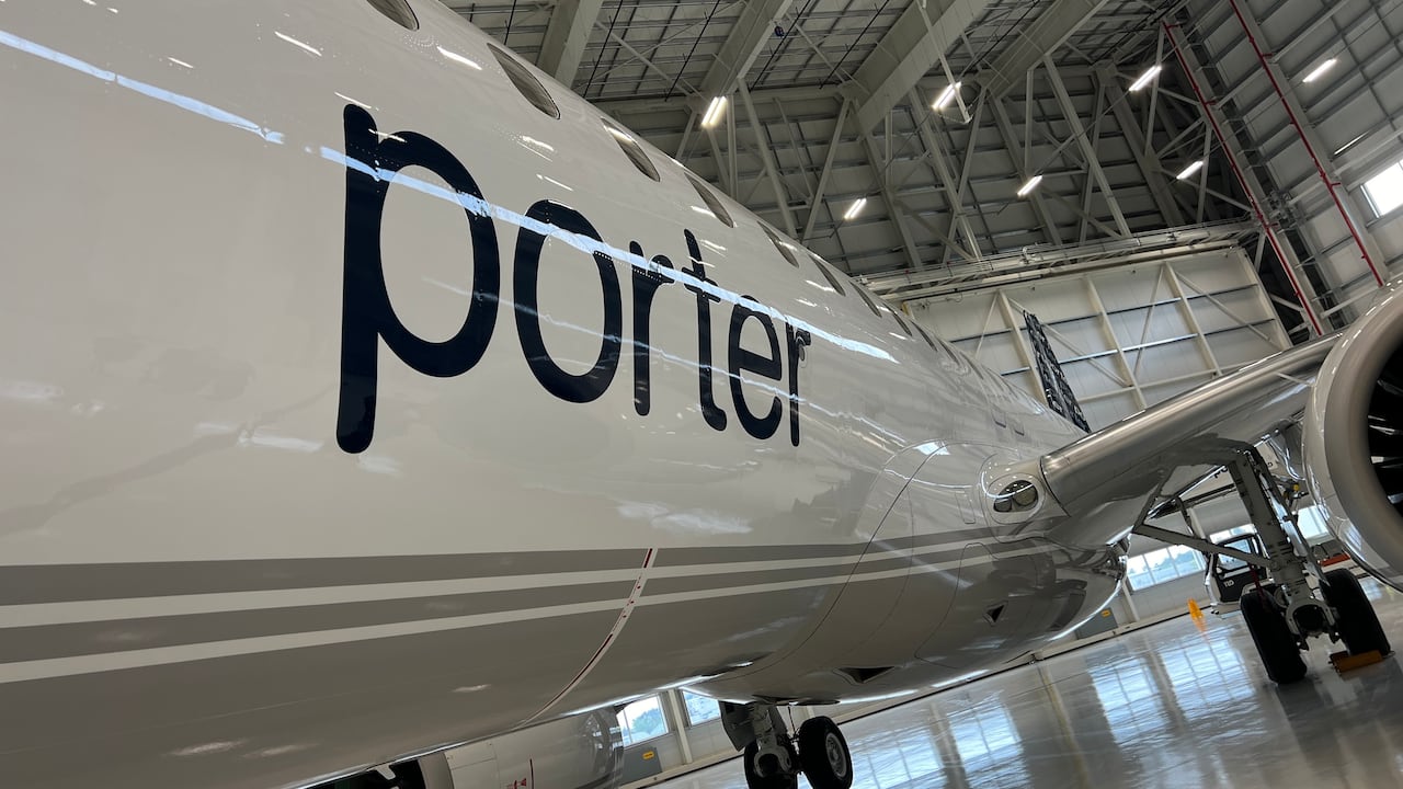 'Porter' in blue on the side of a white passenger plane in a hanger.