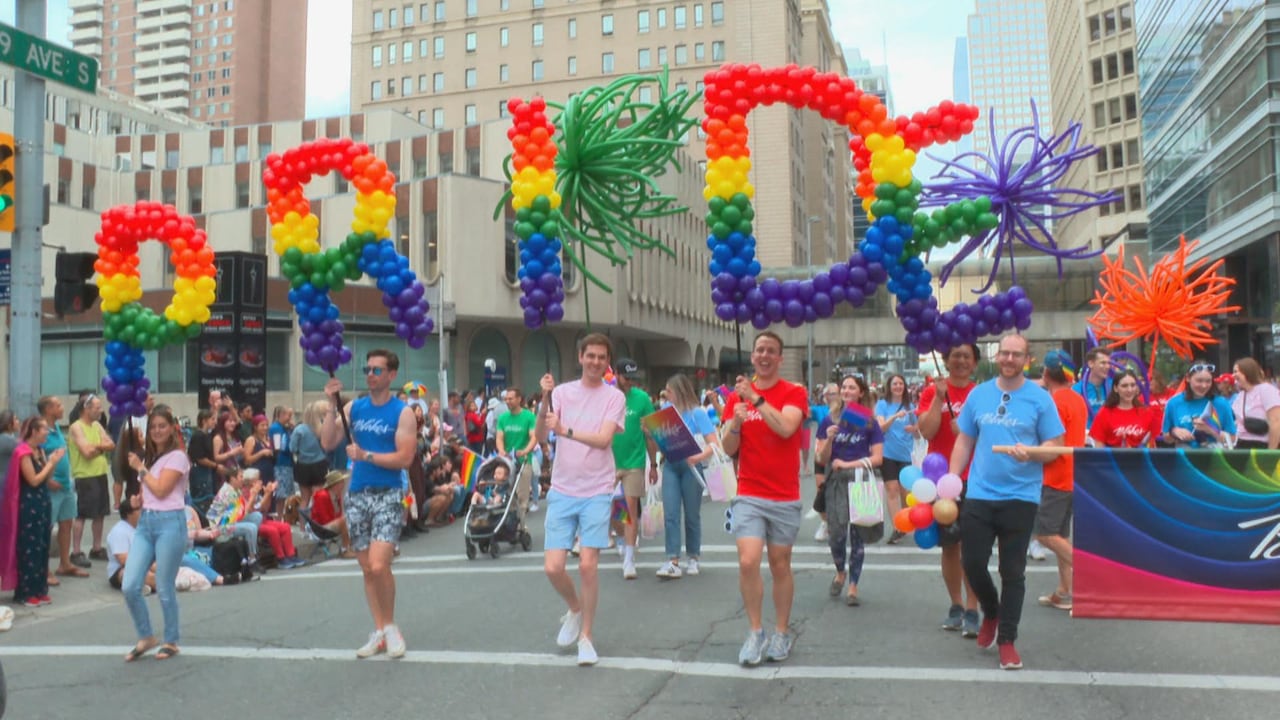 A group of people holding balloons in the shape of the word Pride