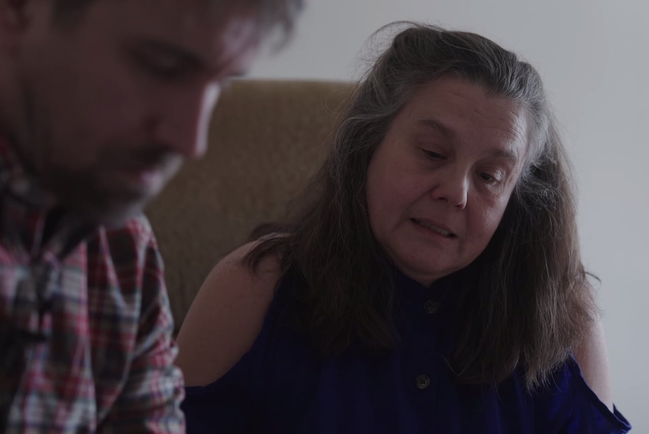 A woman sitting next to a man looking down. 