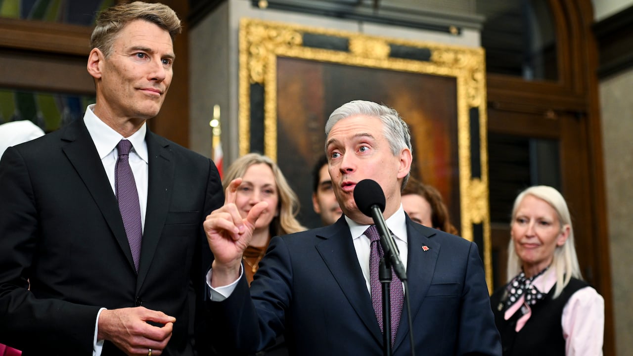 Two men in suits standing in front of a microphone.