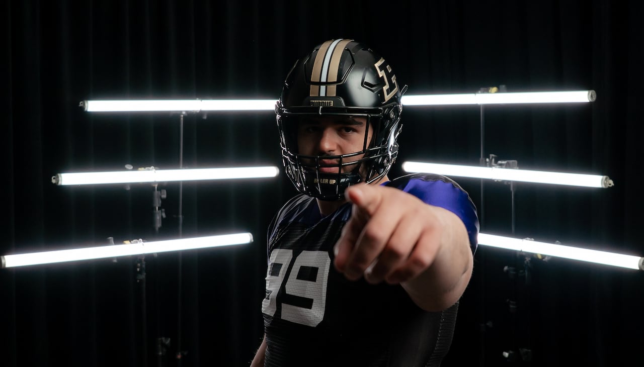 A football player points at the camera while standing in a dark room