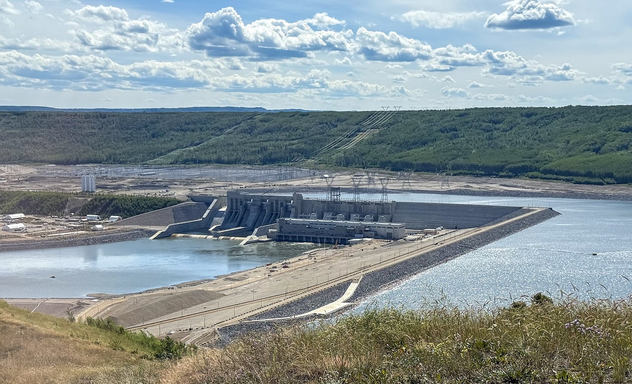 A large earthen dam across a wide river.