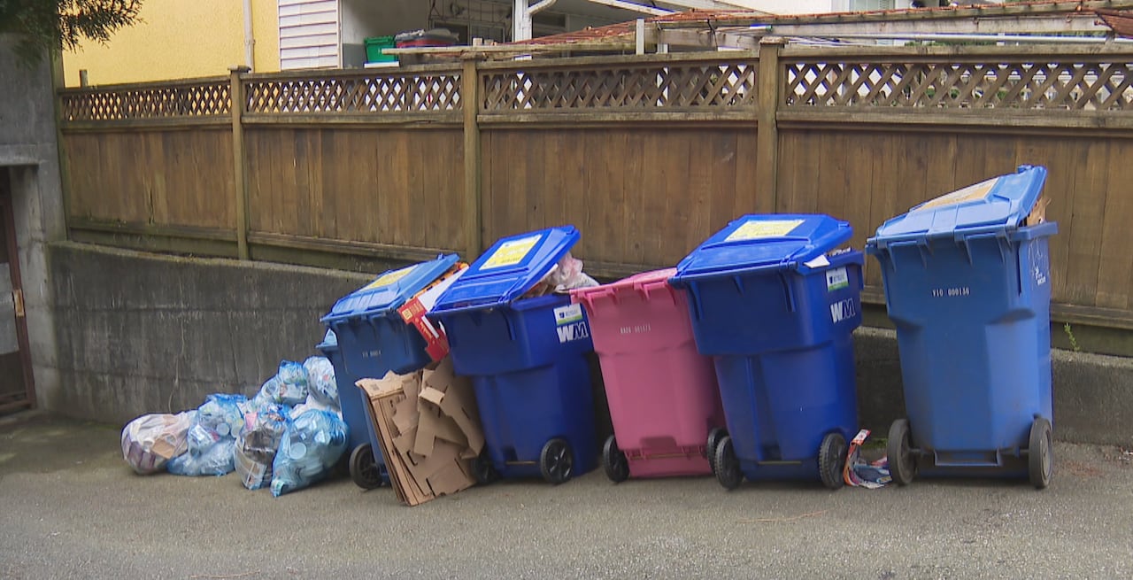 A row of recycling bins with plastic bags next to it.