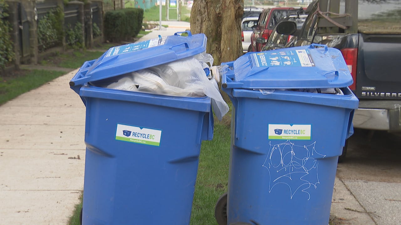 Overflowing recycling bins on a city street.