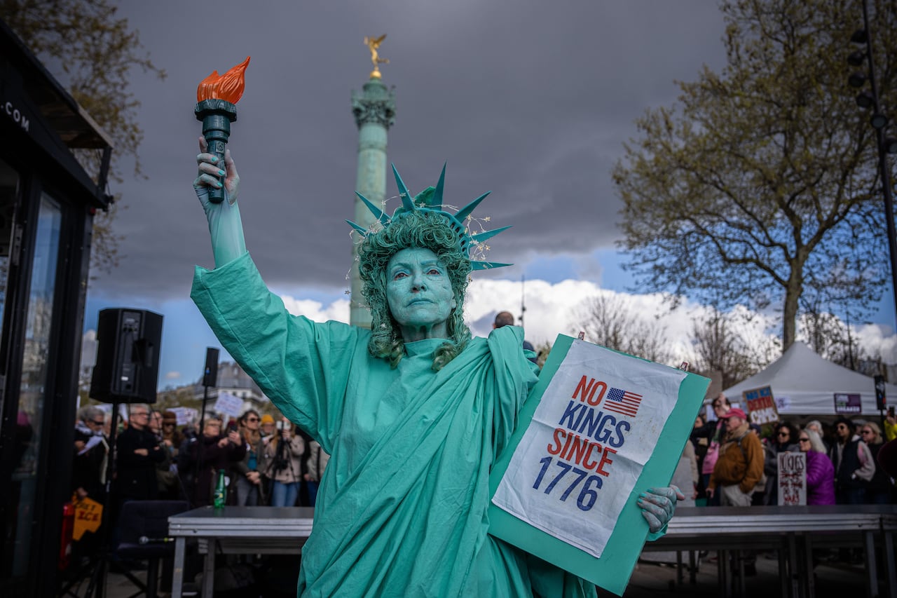 A person dressed as the Statue of Liberty poses during a protest.