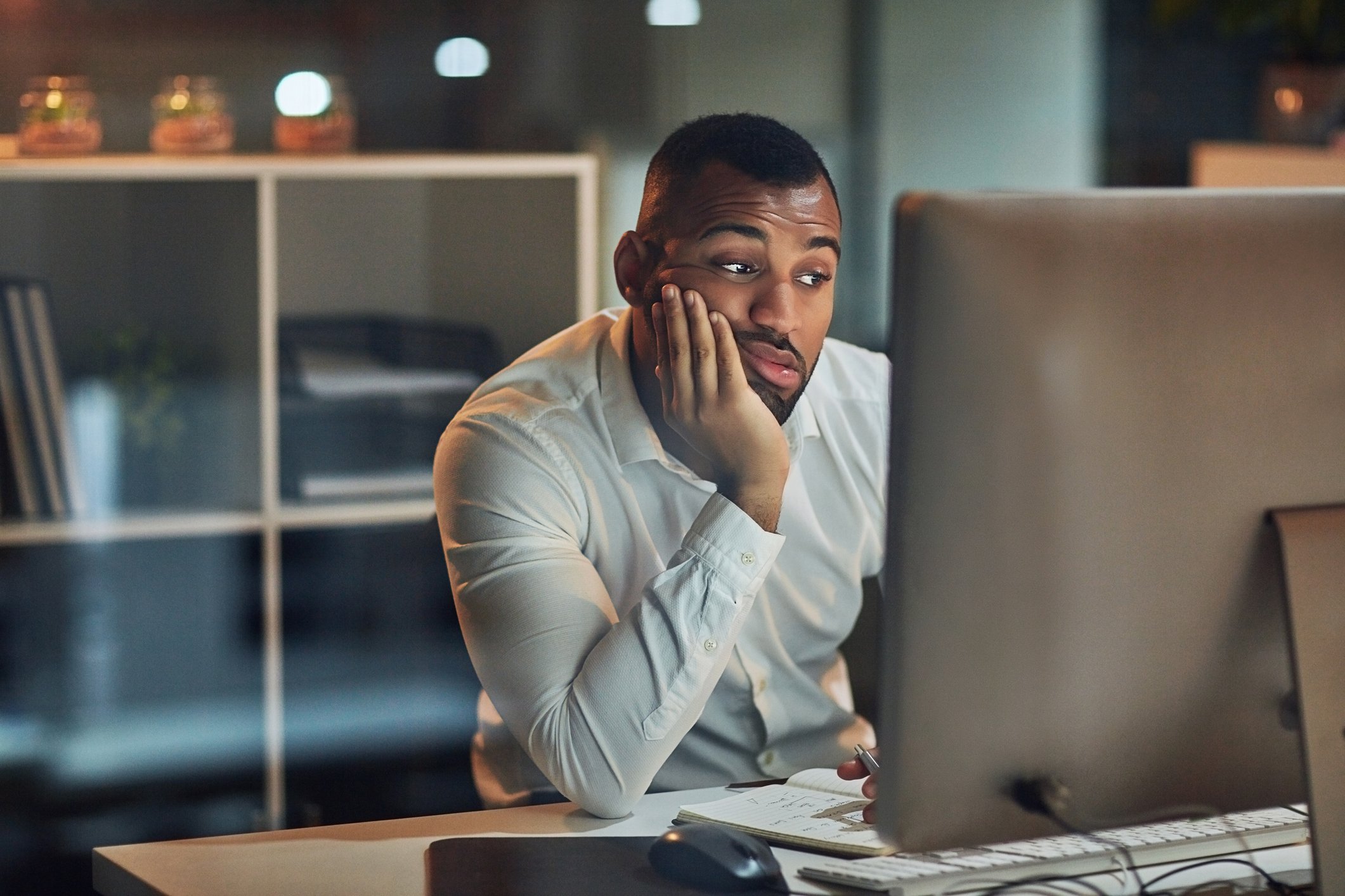 Person with a serious expression looking at a computer.