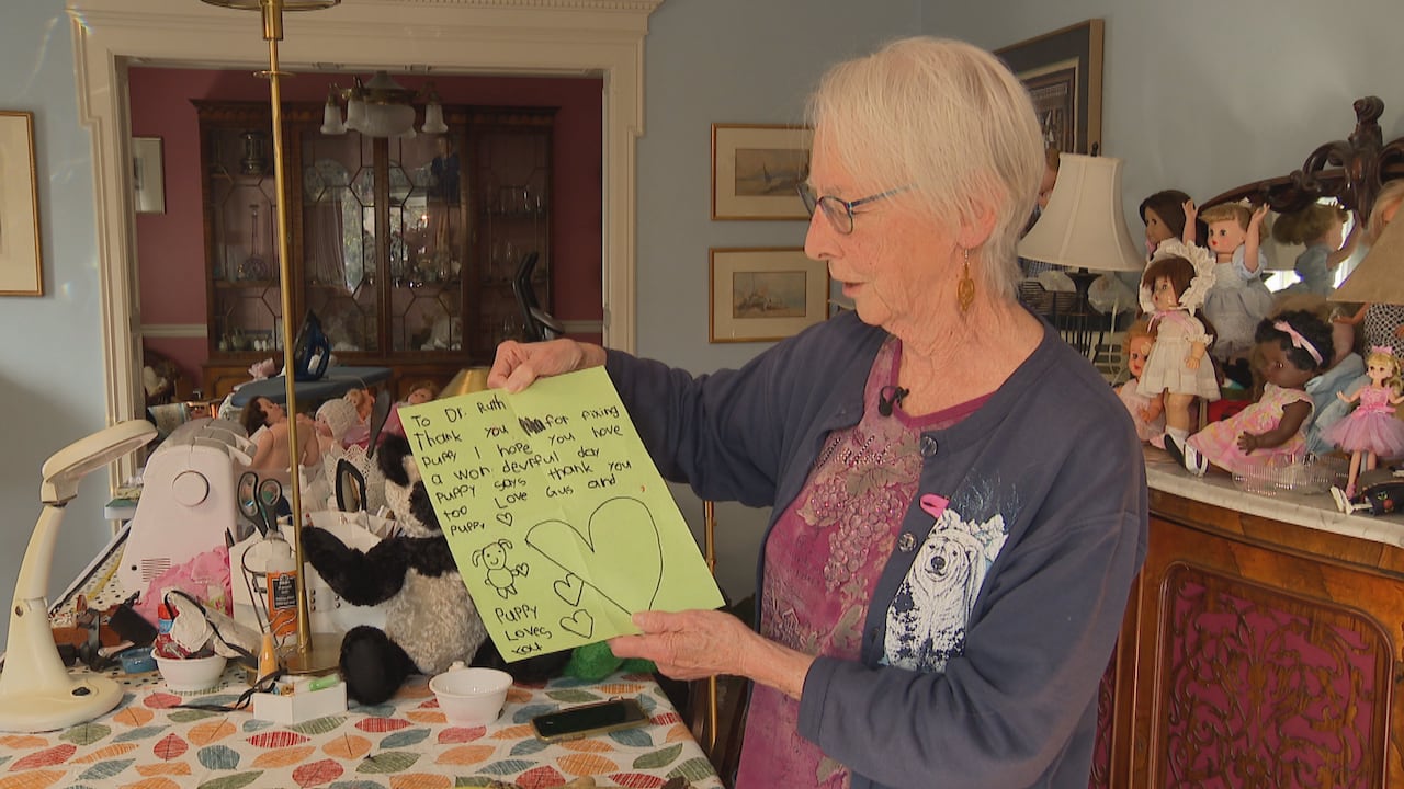 A woman holds up a note that is signed "Puppy loves you"