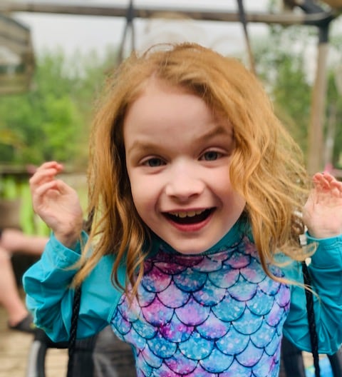 A little girl smiling on a swing.