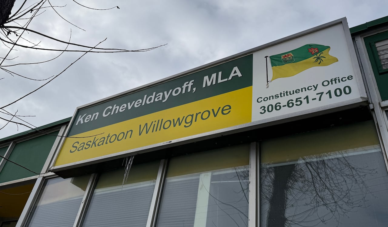 An office building with a glass front and sign reading "Ken Cheveldayoff, MLA Saskatoon Willowgrove."