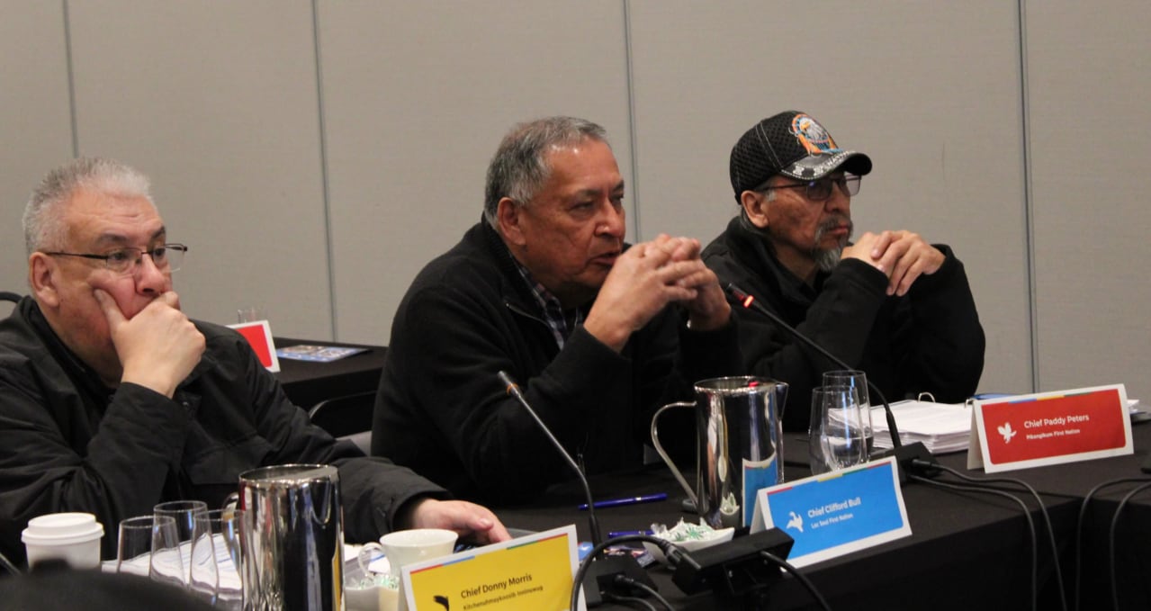 Three people are seen sitting at a table.