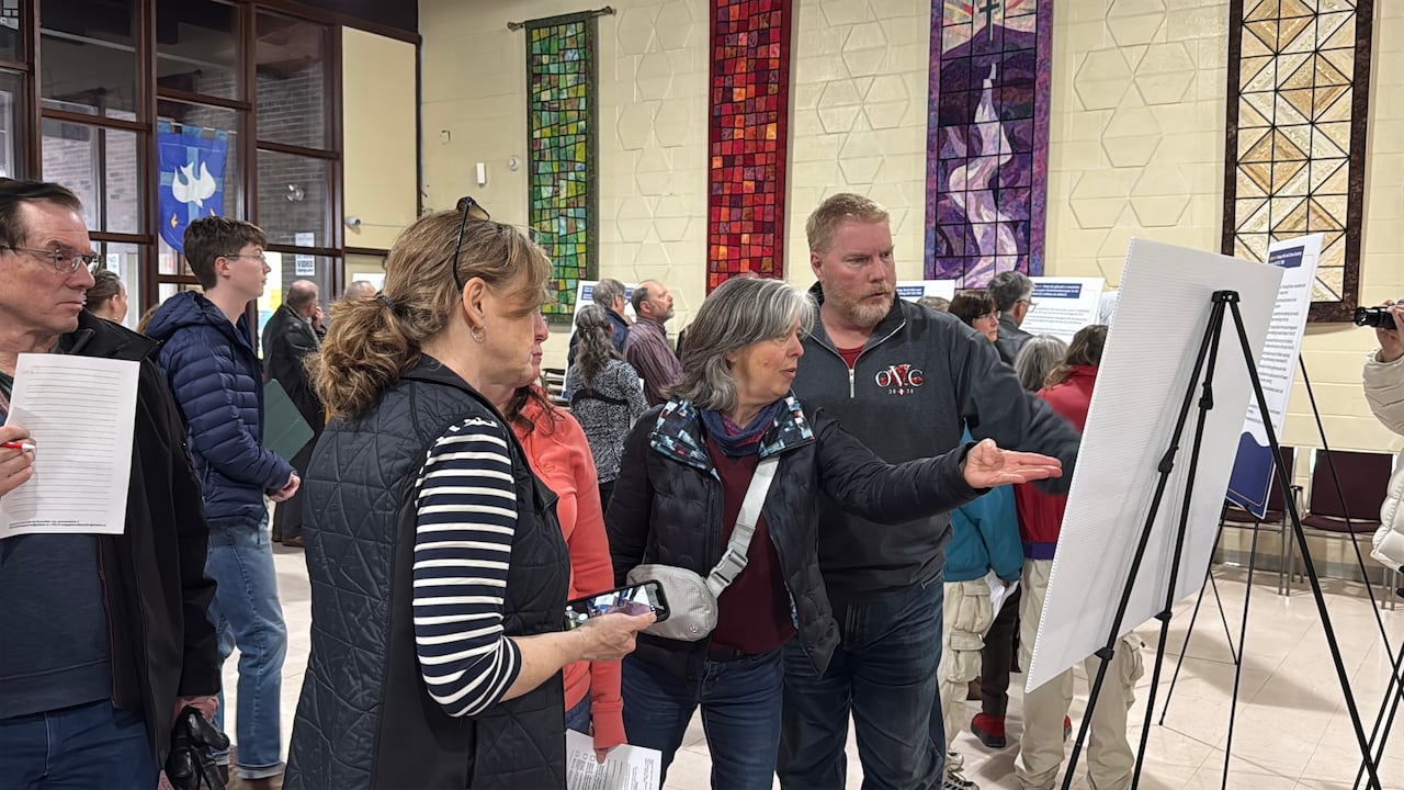 A crowd of people standing in front of an easel