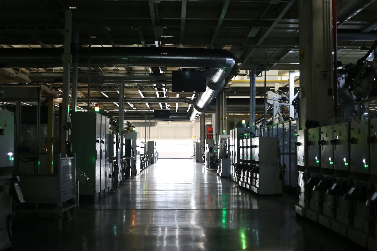 A dark factory floor with the only light coming from a window in the distance.
