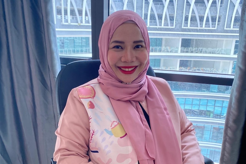 Woman in pink hijab smiling to camera.