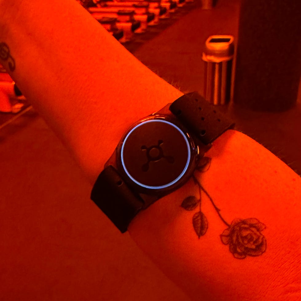 A person’s wrist with a fitness tracker and a rose tattoo.