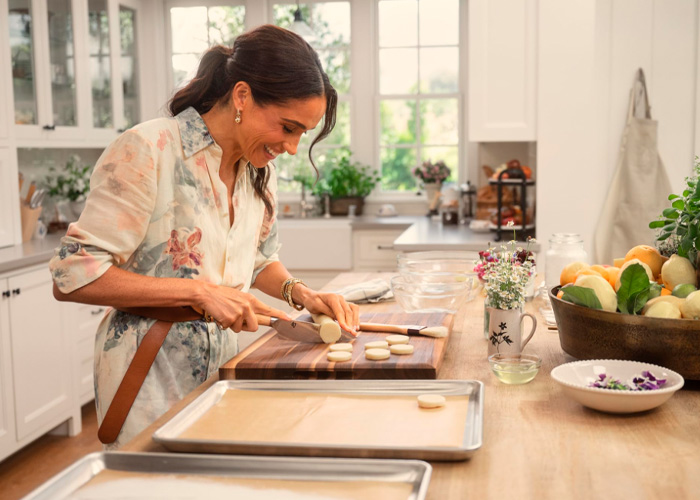 Meghan Markle preparing cookies in a bright kitchen, highlighting Netflix cuts and challenges for As Ever brand.
