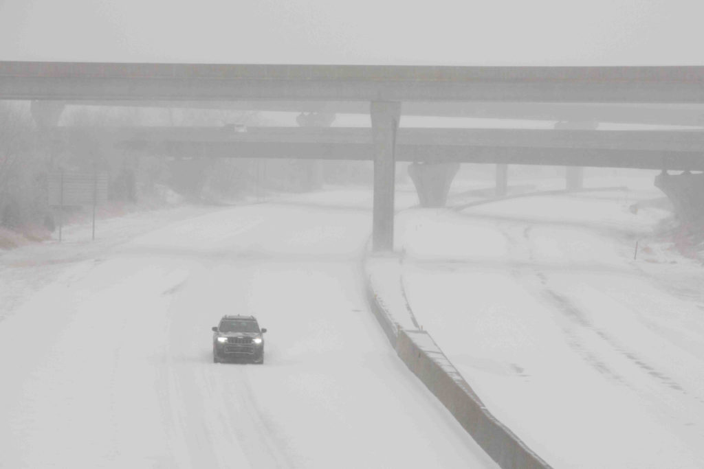 A vehicle travels westbound in blizzard conditions during a winter storm in Topeka