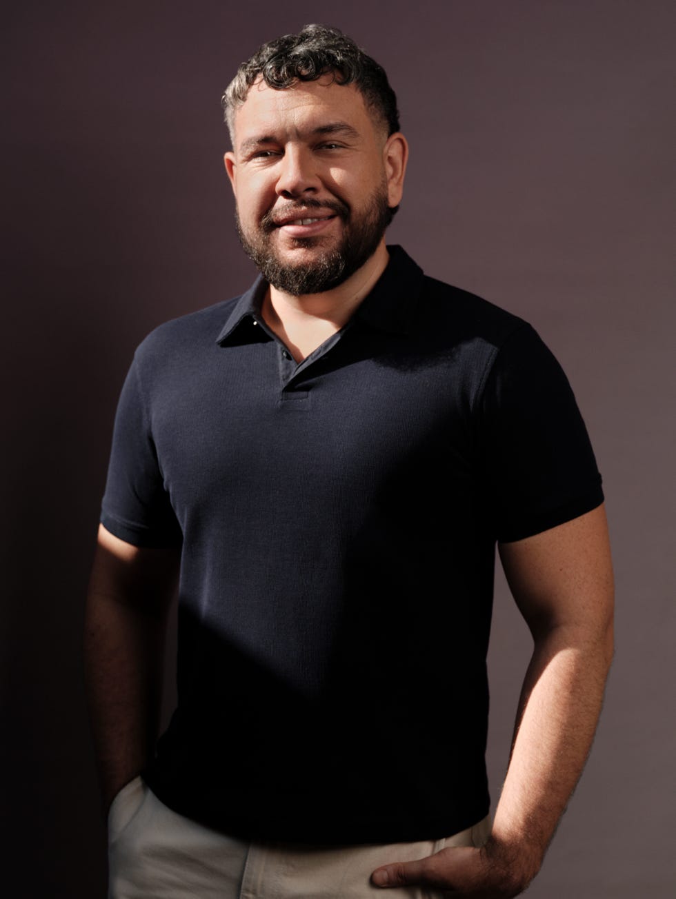 male model wearing a navy blue polo shirt and lightcolored pants