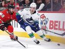 Nils Hoglander of the Vancouver Canucks controls the puck against Matt Grzelcyk of the Blackhawks on March 6 in Chicago.