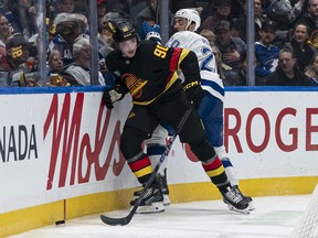 Victor Mancini of the Vancouver Canucks gets away from a hit by Nick Paul of the Tampa Bay Lightning during the second period of NHL action at Rogers Arena on March 19, 2026 in Vancouver.