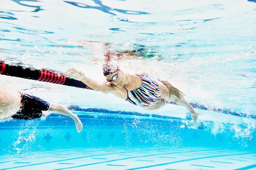 Underwater view of mature female athlete swimming during workout.