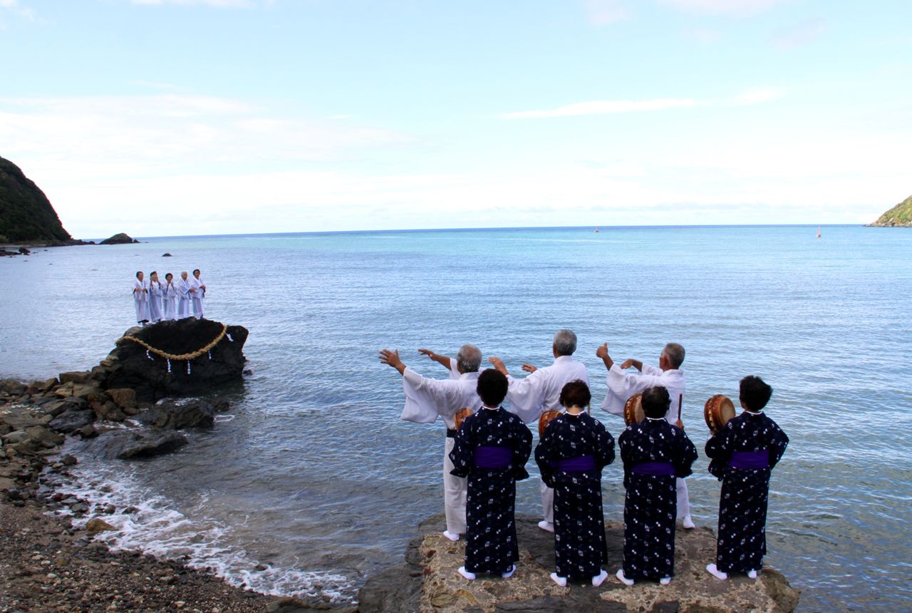 In the Hirase Mankai religious ritual, conducted at dusk, white-clad noro priestesses gather on the shore to summon the deity from over the horizon. (© Hamada Futoshi)