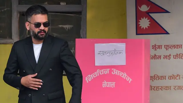 Nepal election 2026 candidate Balendra Shah wearing a suit and standing in a voting station