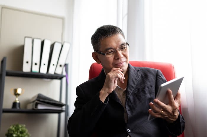 A smiling person looking at a tablet.