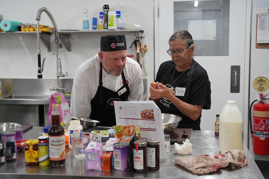 A man and a woman speak in a commercial kitchen.